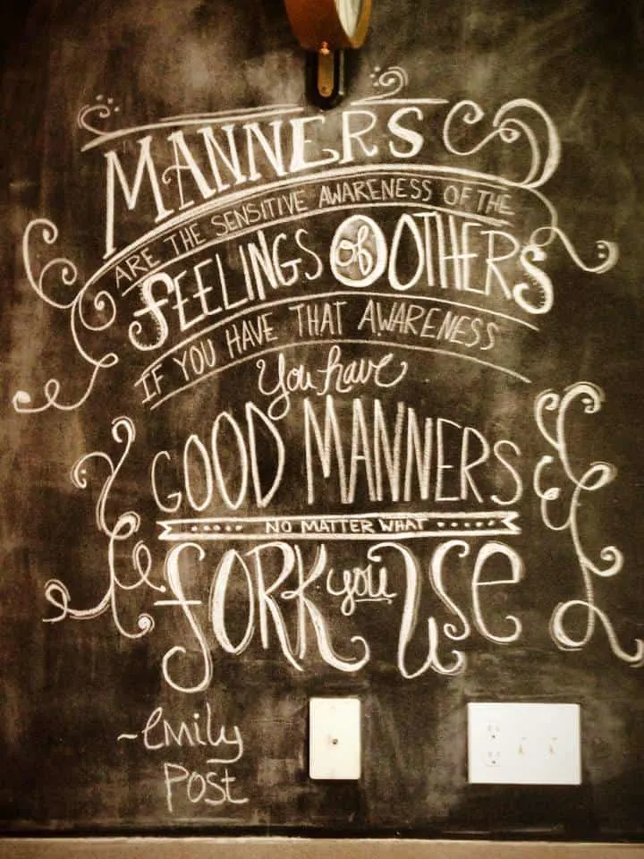 An artistic chalkboard wall that says, "Manners are the sensitive awareness of the feelings of others if you have that awareness you have good manners no matter what fork you use - Emily Post".