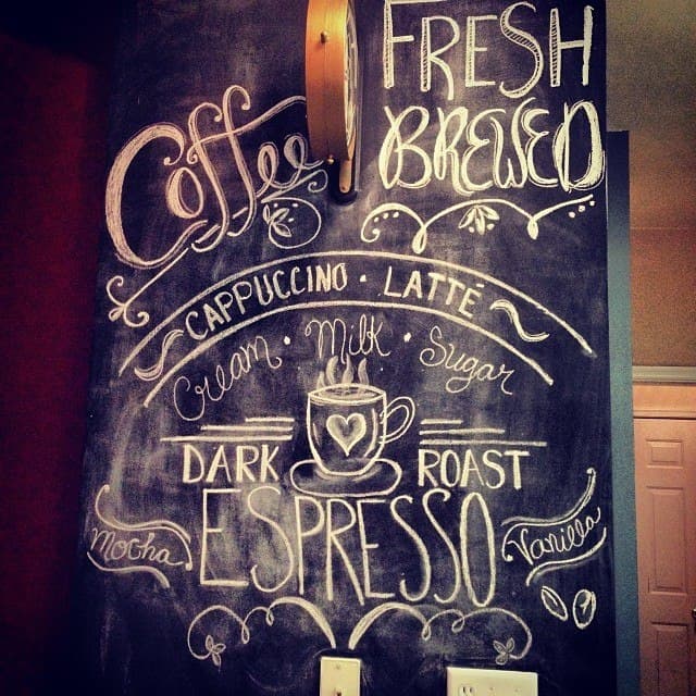 an artistic drawing on a chalkboard wall that says, "coffee, fresh brewed, cappuccino, latte, cream, milk, sugar, dark roast espresso, mocha, vanilla".