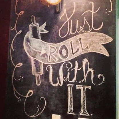 a chalk drawing of a rolling pin with text that says, "Just roll with it".