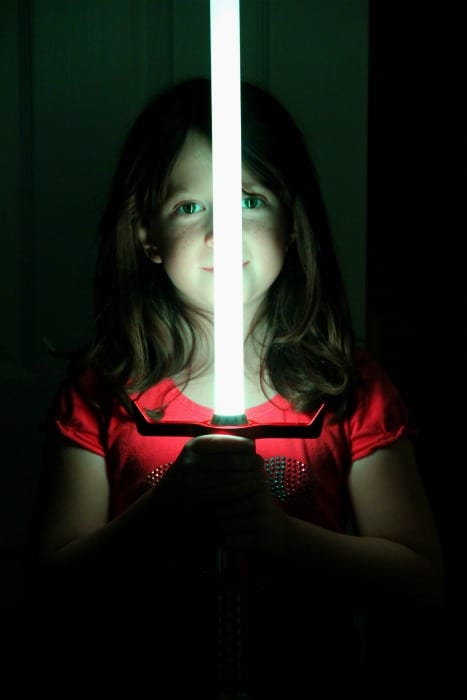 little girl holding a Kyberlight lightsaber