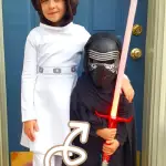 Two kids dressed up as Princess Leia and Kylo Ren with a text overlay that says, "Kyberlight Review - High Quality lightsabers for kids and adults".