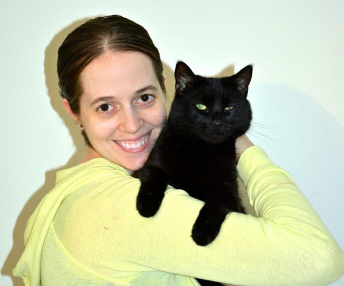 a woman holding a black cat in her arms.