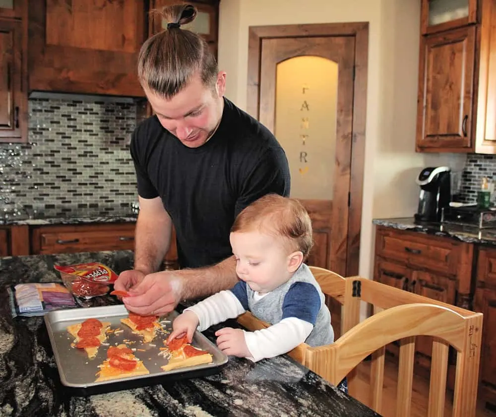 father and toddler making pizza rolls