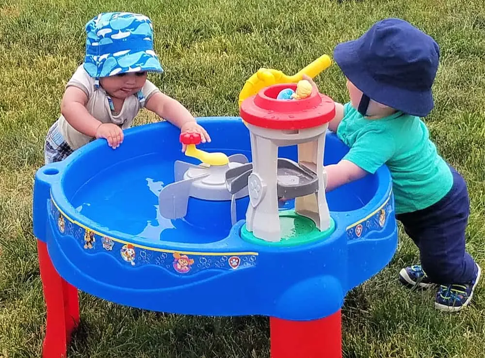 2 toddlers playing by water table