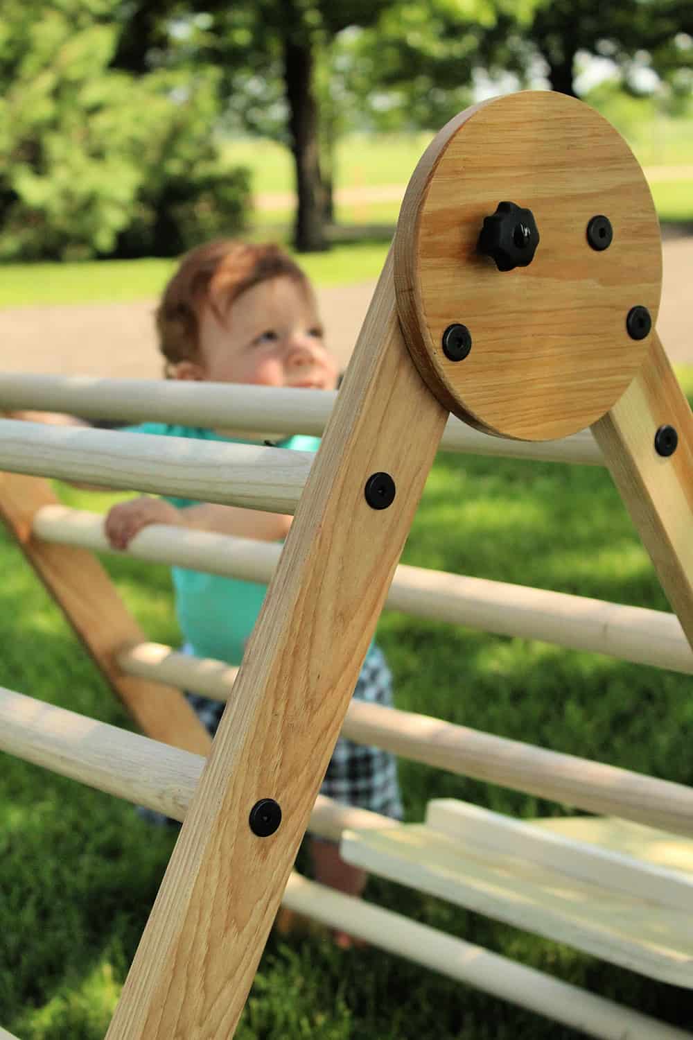 toddler climbing wooden triangle