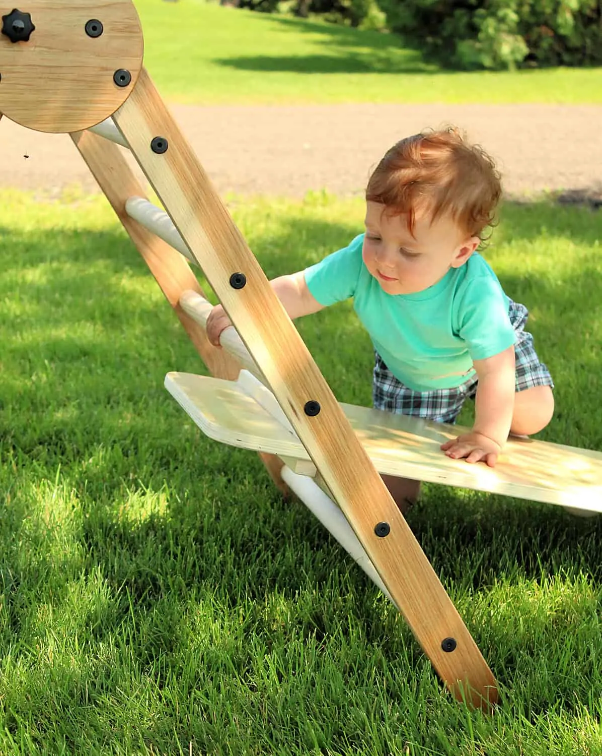 toddler climbing wooden triangle