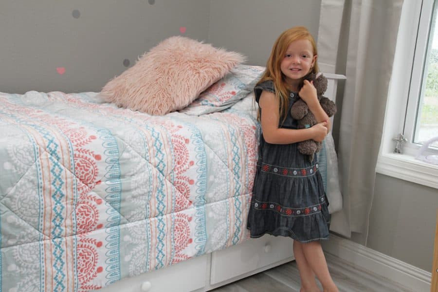 girl standing by bed - Benefits Of Sleep For Kids + Storkcraft Marco Island Trundle Captain’s Bed Review