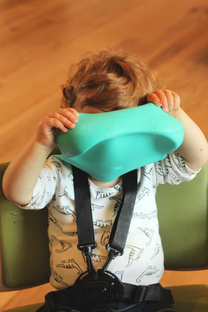 toddler in highchair with bib over face