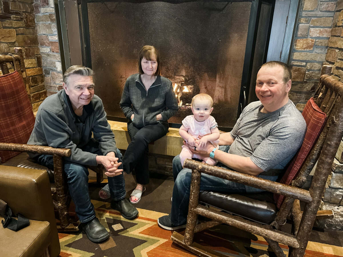 grandparents, baby, and dad sitting by fire - Great Wolf Lodge Is A Perfect Place For Family Reunions and Large Groups