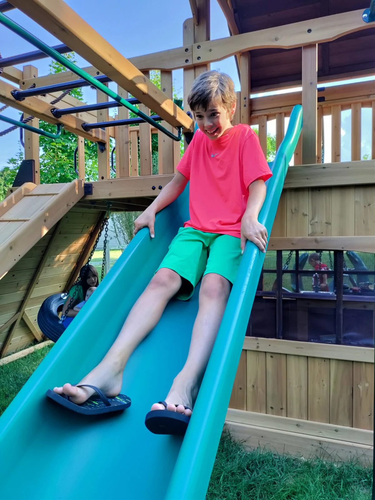 boy sliding down a green slide